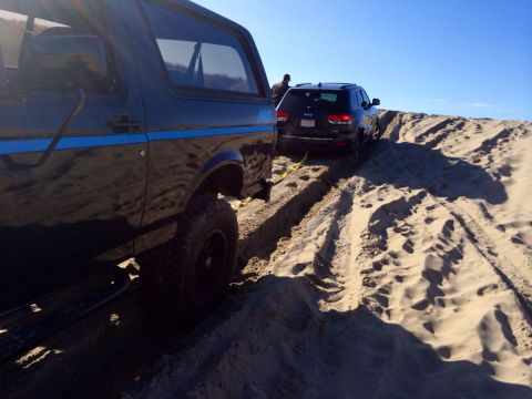1992 Ford Bronco - A 1992 Ford Bronco is partially visible on the left, stuck in sand, with a Jeep Grand Cherokee behind it.