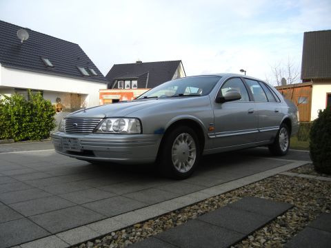 1999 Ford Fairlane - A silver sedan is parked on a tiled driveway with houses in the background.