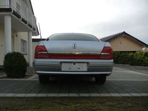 1999 Ford Fairlane - Rear view of a silver sedan parked in a driveway, showing its taillights and trunk.