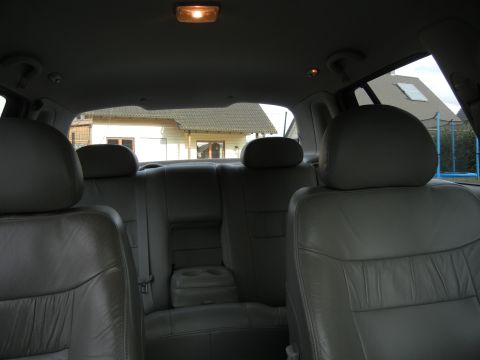 1999 Ford Fairlane - Interior view of a car's back seats and headrests, with houses seen through the windows.