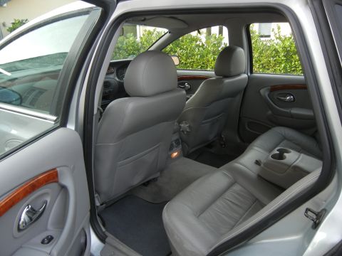 1999 Ford Fairlane - The spacious interior of a silver sedan, grey leather seats and wood trim accents on the door panel.