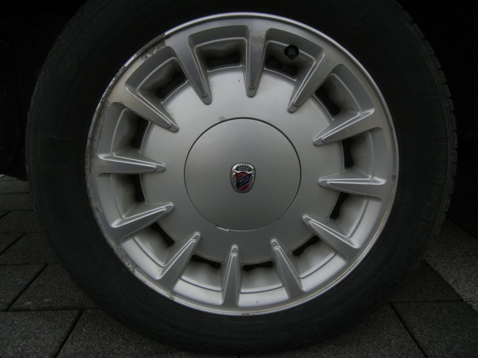 Close-up of a silver alloy wheel with a red and blue emblem in the center