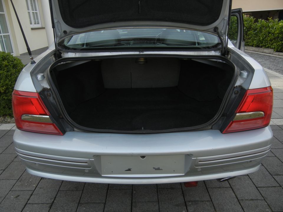 Silver sedan's open trunk, rear bumper visible. Supermotors.net logo at bottom right