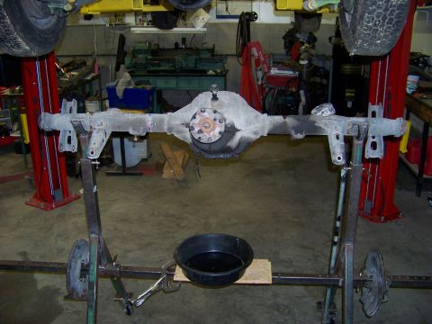 1999 Mercury Grand Marquis - A rear axle assembly is shown on a stand in a workshop, with a drain pan underneath.