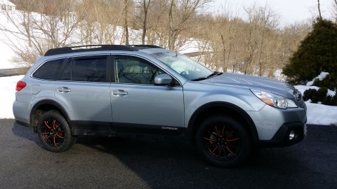 2014 Subaru Outback - The side profile of a silver Subaru Outback shows its distinctive body style and aftermarket wheels.