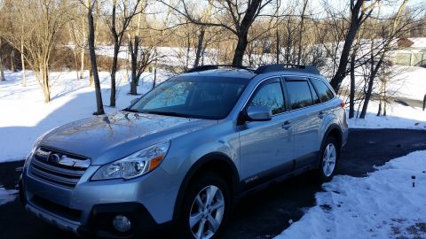 2014 Subaru Outback - This silver 2014 Subaru Outback features dark window visors and is parked outdoors in a snowy environment.