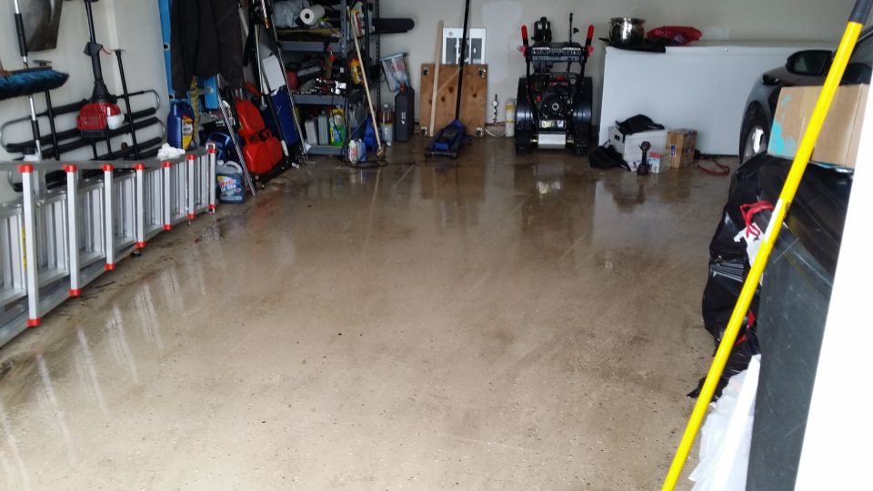 garage interior with ladders, snowblower, and a car partially visible on the right
