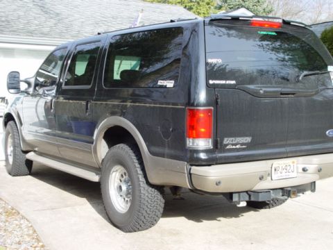 2003 Ford Excursion - The rear of a black 2003 Ford Excursion is shown, tinted windows and a trailer hitch. The license plate is visible.