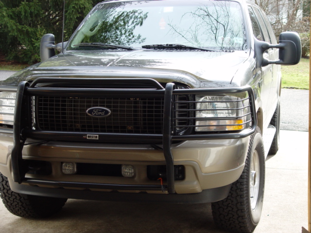 Dark Ford Excursion SUV with black Westin brush guard, front 3/4 view in driveway