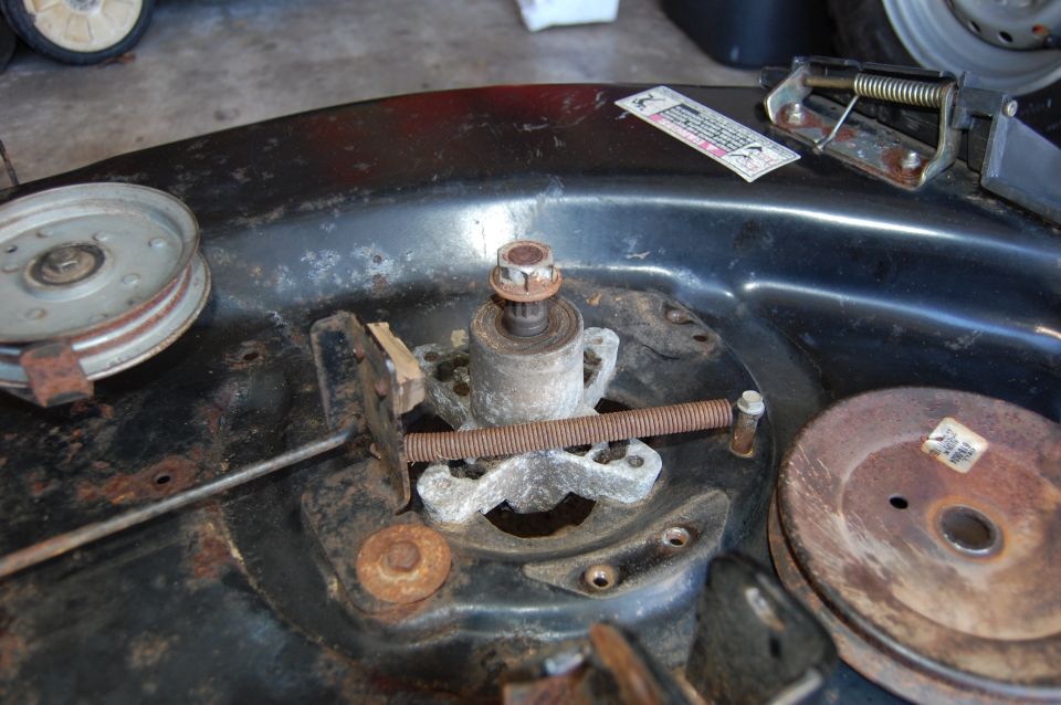 Rusty lawn mower deck with pulley, spindle, and adjustment screw