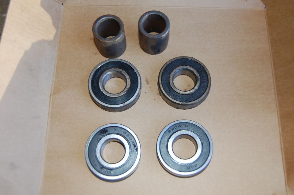 Four ball bearings and two metal bushings on a cardboard surface