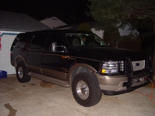 2003 Ford Excursion - A black 2003 Ford Excursion is parked outside a garage at night.