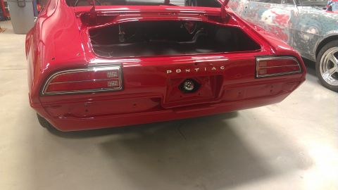 1972 Pontiac Trans Am - Rear view of a red 1970 Pontiac Firebird, showing the trunk area and taillights. Another vehicle is visible.