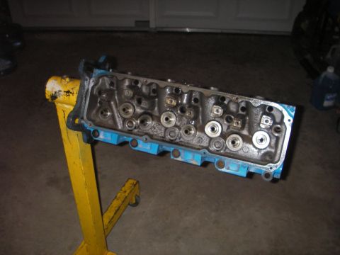 1972 Ford Ranchero - Engine cylinder head on a yellow stand, ready for rebuild or inspection.