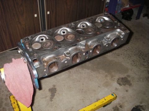 1972 Ford Ranchero - Engine cylinder head with valves visible, resting on yellow supports in a garage.
