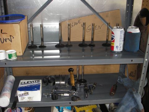 1972 Ford Ranchero - Various engine parts, including valves and bearings, are organized on a workshop shelf.