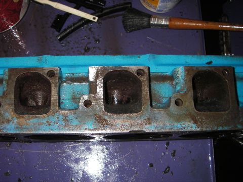 1972 Ford Ranchero - A dirty engine cylinder head sits on a purple surface, with brushes and other cleaning supplies nearby.