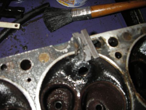 1972 Ford Ranchero - Close-up of an engine cylinder head being cleaned with a brush, with a small metal piece attached.