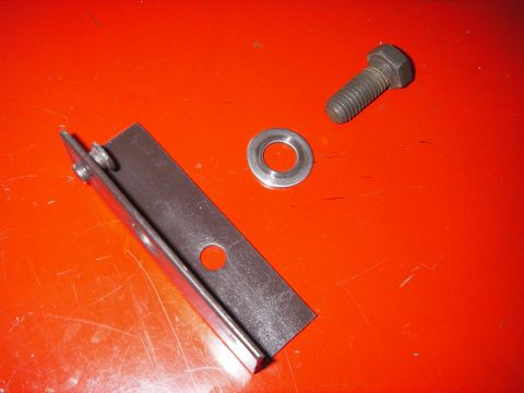 1972 Ford Ranchero - A metal bracket, bolt, and washer are laid out on an orange surface, with the Supermotors.net logo in the lower right corner.