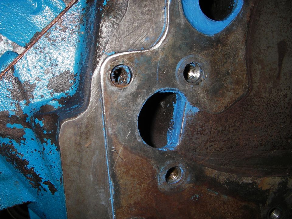 Close-up of an engine block with blue sealant around bolt holes
