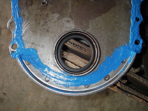 1972 Ford Ranchero - A close-up view of an engine component being prepped with blue sealant, with cardboard visible in the background.