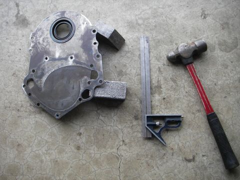 1972 Ford Ranchero - Engine timing cover, seal, square, and hammer are laid out on a concrete surface.