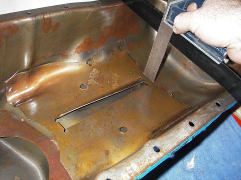 1972 Ford Ranchero - A hand uses a square to mark a modification on a rusty oil pan.
