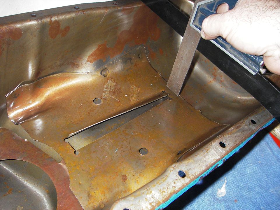 guy cutting metal on rusty oil pan with a square