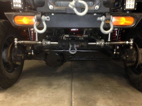 1987 Suzuki Samurai - Close-up view of a vehicle's front axle, steering components, and tow hooks.
