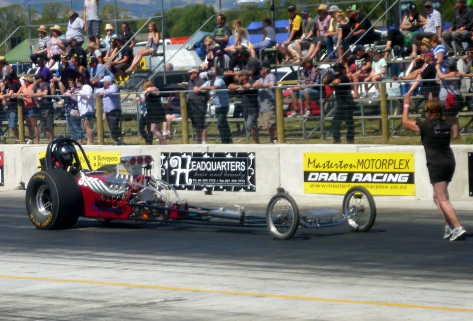 Dragster with large rear tires and exposed engine, side view