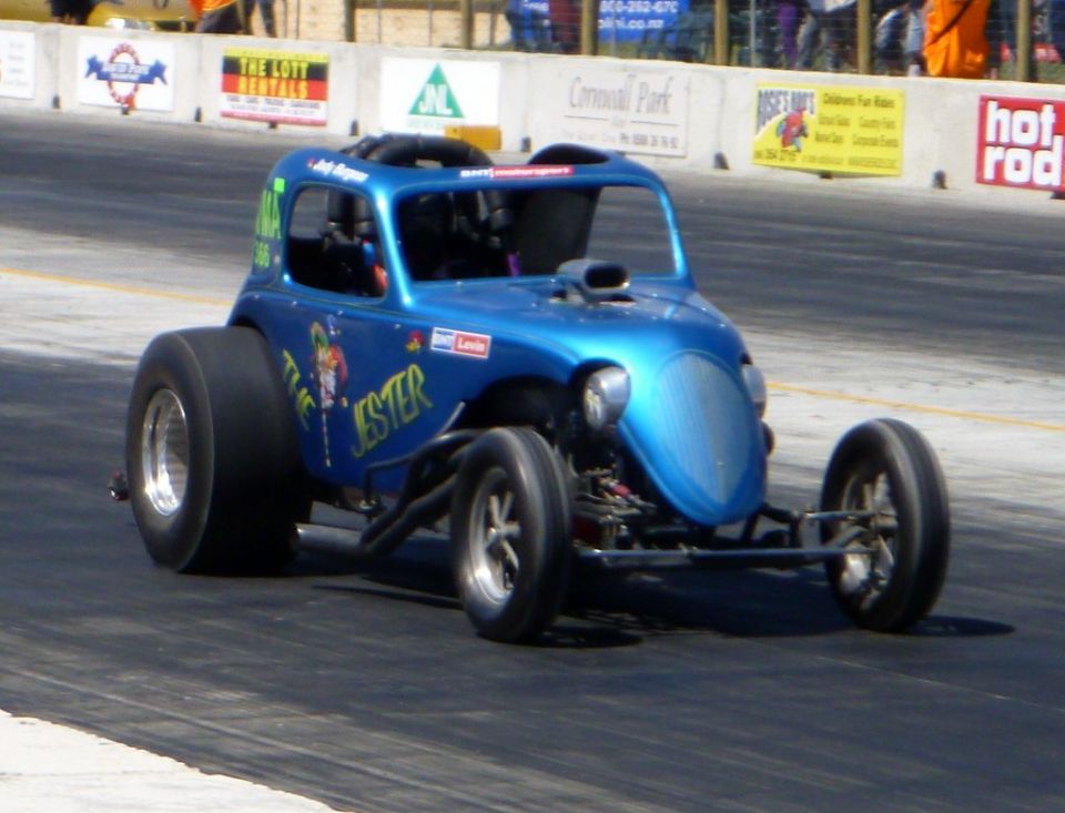 blue drag car with 'The Jester' painted on side, racing on track
