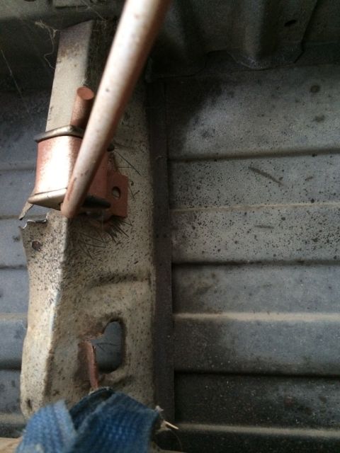 1964 Ford Ranchero - Close-up of a damaged underbody component, possibly a fuel tank strap, showing rust and wear.