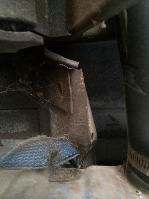 1964 Ford Ranchero - A close-up view of a rusted bracket and a blue strap, likely part of a vehicle's undercarriage.