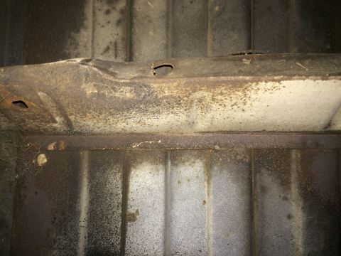 1964 Ford Ranchero - Close-up of a corroded vehicle undercarriage frame, showing signs of wear and damage.
