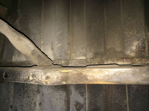 1964 Ford Ranchero - Underside view of a cracked metal strap, likely a fuel tank strap.