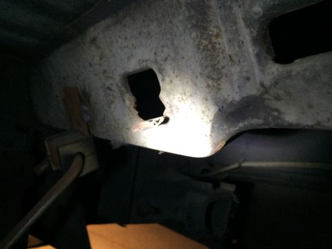 1964 Ford Ranchero - Close-up of a corroded metal frame with a hole, likely a fuel tank strap attachment point.