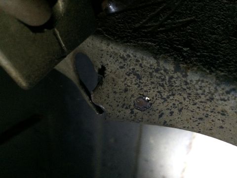 1964 Ford Ranchero - Close-up view of a rusted metal frame showing a hole and signs of wear.
