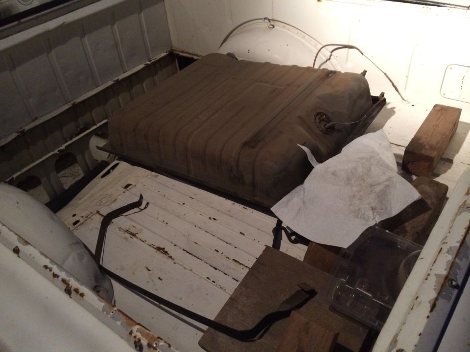 Fuel tank sitting in the bed of a pickup truck, next to some wood blocks and paper