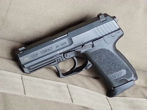 2003 Ford Crown Victoria - A black USP Compact .40 S&W pistol rests on a tan fabric surface.