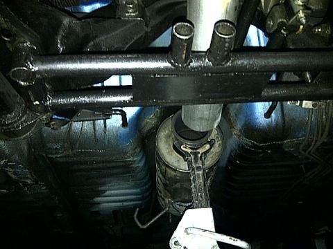 1995 Ford Probe - The underside of a vehicle shows the exhaust system, including the muffler and pipes, with a jack holding it up.
