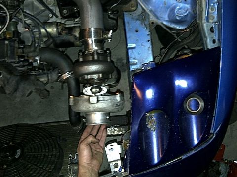 1995 Ford Probe - Close-up view of a turbocharger being installed in a blue vehicle's engine bay.