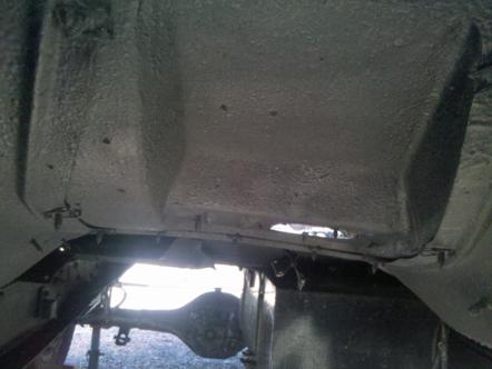 1982 Ford Bronco - The underside of a vehicle is shown, with a view of the frame and rear axle assembly.