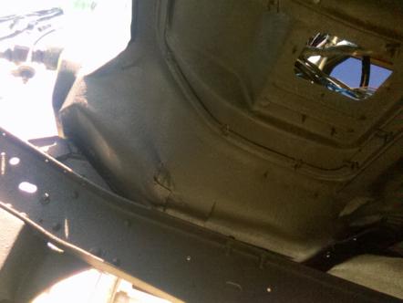 1982 Ford Bronco - The underside of a vehicle's chassis and body panels are visible, with a hole in the floor revealing wiring and the sky.