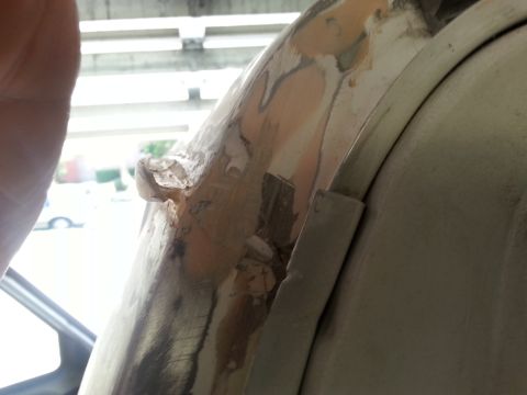 1992 Ford Bronco - Close-up of vehicle bodywork undergoing repair, revealing primer and filler on a damaged section.