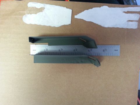 1992 Ford Bronco - Two green trim pieces are laid out and measured with a metal ruler against a brown background.