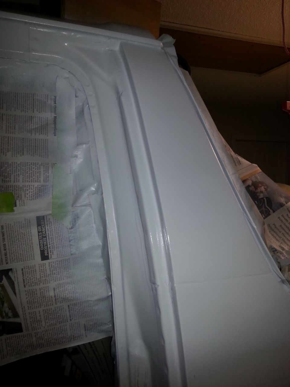 White vehicle body panel with taped-off area covered in newspaper