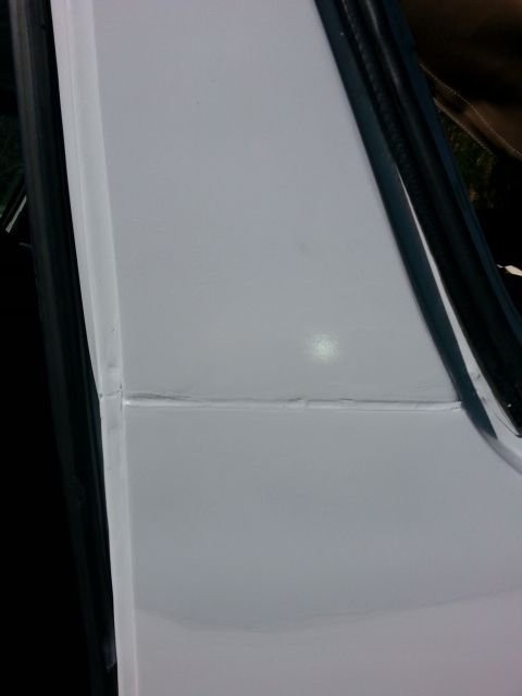 1992 Ford Bronco - Close-up of a white vehicle's door seam, showing evidence of repair work and a black rubber seal.