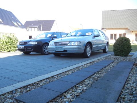 1999 Ford Fairlane - This silver sedan, likely not a 1999 Ford Fairlane, is parked in a driveway alongside a dark Audi.