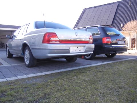 1999 Ford Fairlane - Two cars are parked in a driveway, one silver sedan and one black wagon.