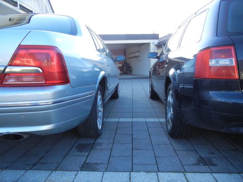 1999 Ford Fairlane - Two cars are parked in a driveway, one light blue sedan and one black wagon.